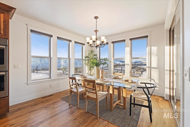 dining room featuring plenty of natural light, a notable chandelier, a mountain view, and light hardwood / wood-style flooring