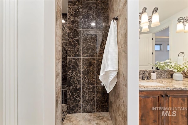 bathroom with tiled shower and vanity