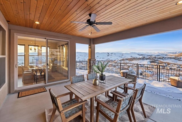 snow covered patio with a mountain view and ceiling fan