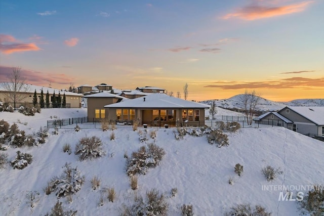 snow covered rear of property featuring a mountain view