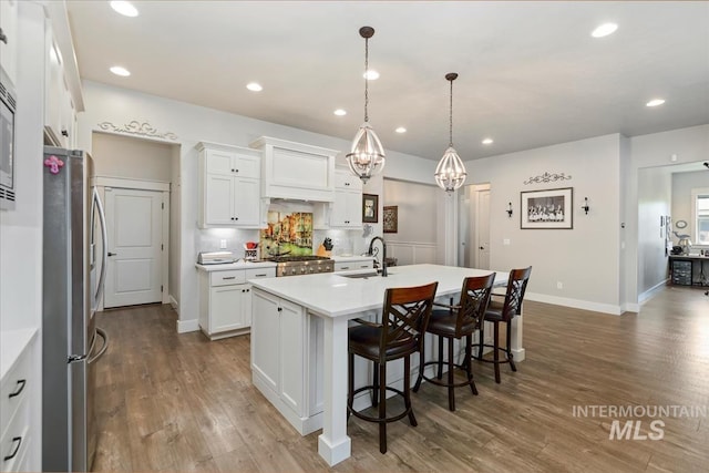 547 S Rivermist Ave, Star, ID 83669 - kitchen with freestanding refrigerator, wood finished floors, a kitchen bar, light countertops, and recessed lighting