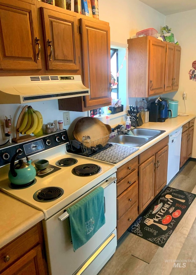 830 Riverside Ave, Orofino, ID 83544 - kitchen with white appliances, exhaust hood, a sink, light countertops, and brown cabinetry