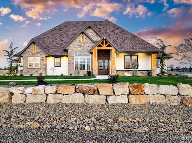 view of front of property featuring french doors, stone siding, a front yard, and stucco siding