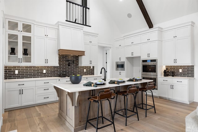 kitchen featuring decorative backsplash, appliances with stainless steel finishes, white cabinetry, and a breakfast bar area