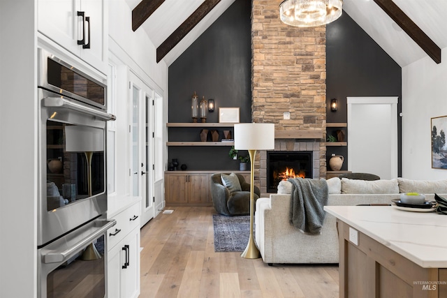 living room with light wood-style flooring, beam ceiling, and high vaulted ceiling