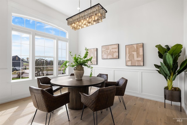 dining room with an inviting chandelier, a decorative wall, and light wood-style flooring