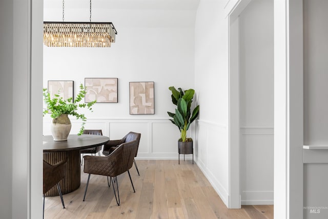 office featuring light wood-type flooring, wainscoting, a notable chandelier, and a decorative wall