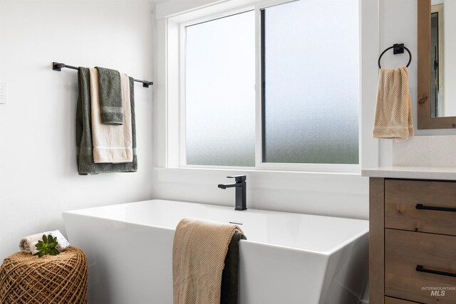 full bath with a freestanding tub, a wealth of natural light, and vanity