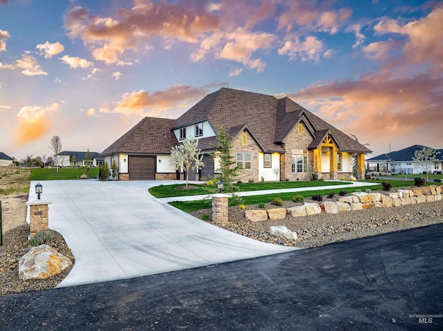 view of front of home with a garage, driveway, stone siding, and a lawn