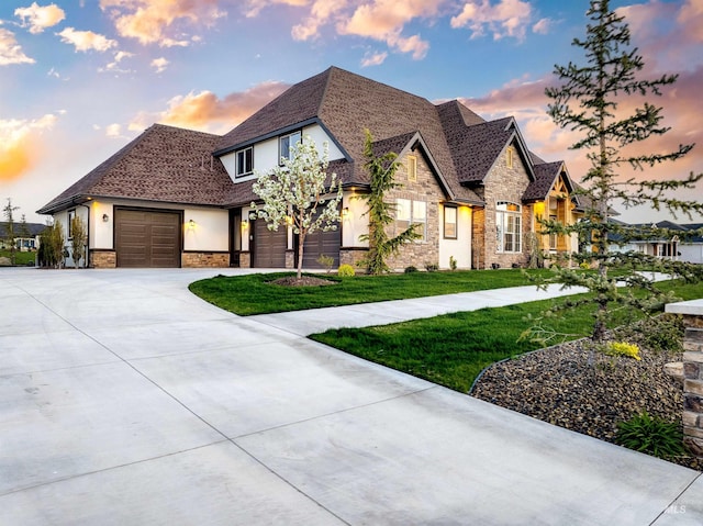 view of front of house with a front lawn, driveway, stone siding, a garage, and stucco siding