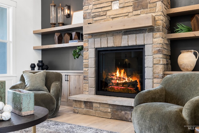 living area with a stone fireplace and wood finished floors