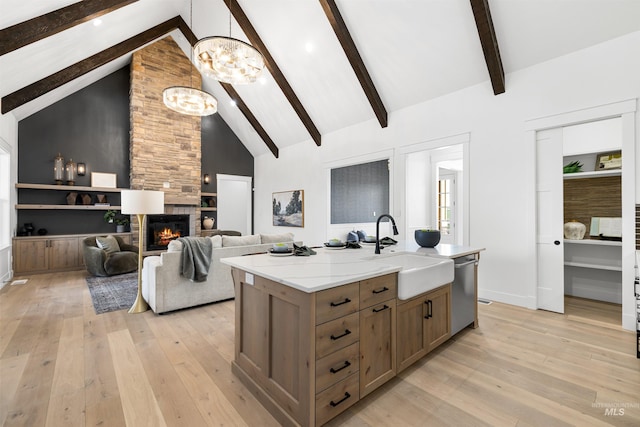kitchen featuring light wood-type flooring, dishwasher, a sink, and beamed ceiling