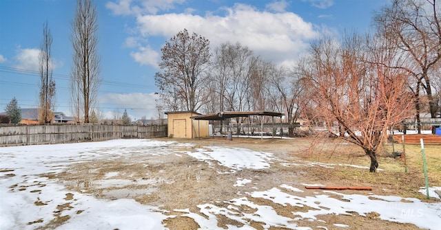 yard covered in snow featuring a shed and a carport