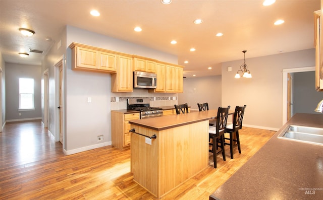 kitchen with tasteful backsplash, stainless steel appliances, decorative light fixtures, light brown cabinets, and sink