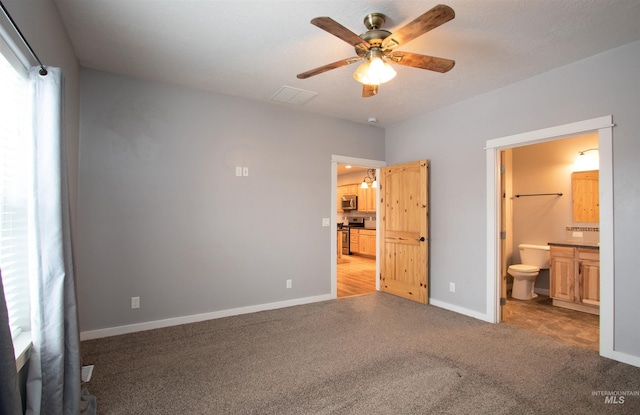 unfurnished bedroom with light carpet, ceiling fan, and connected bathroom