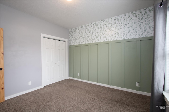 unfurnished bedroom with a closet and dark colored carpet