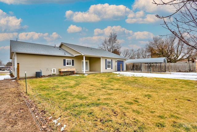 back of property with central AC, a carport, and a yard