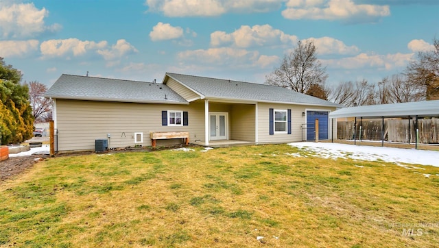 rear view of house with central AC unit and a yard