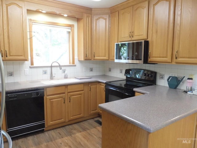 kitchen with a sink, black appliances, and light brown cabinets