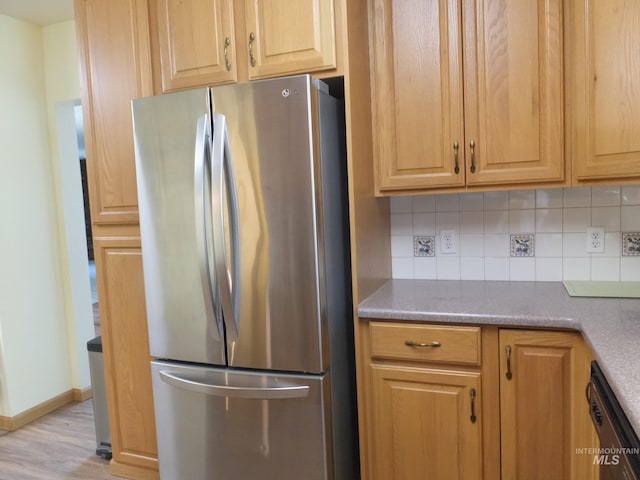 kitchen featuring tasteful backsplash, dishwasher, freestanding refrigerator, baseboards, and light wood-type flooring