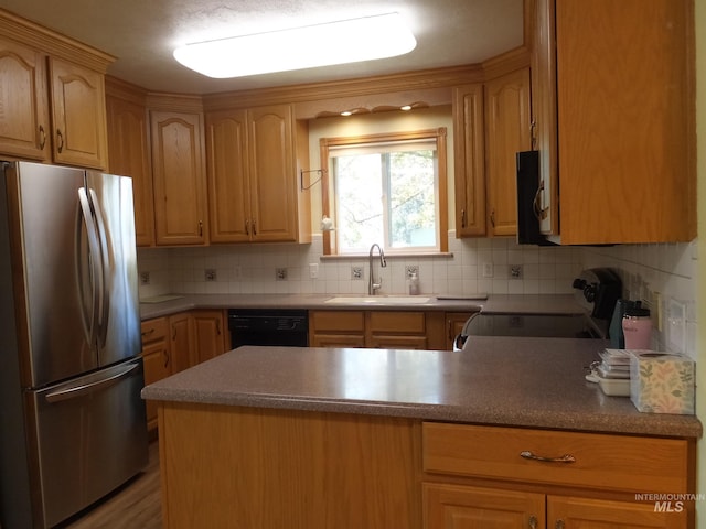 kitchen with a sink, decorative backsplash, freestanding refrigerator, and black dishwasher