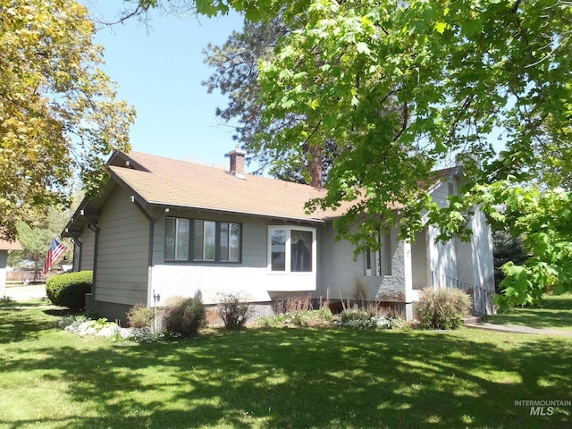 view of front facade with a chimney and a front yard