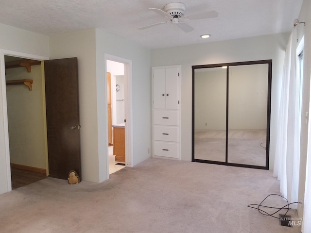 unfurnished bedroom featuring a closet, ensuite bathroom, carpet flooring, and ceiling fan