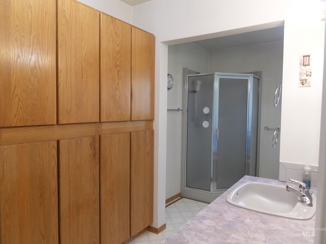 bathroom with tile patterned floors, a shower stall, and a sink