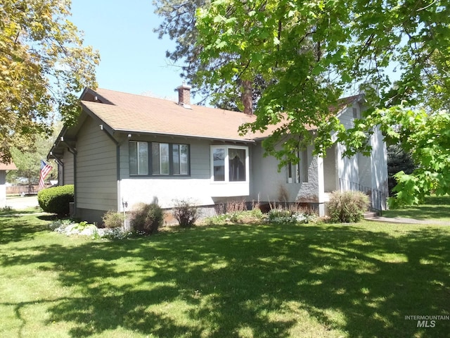 view of front facade featuring a chimney and a front yard