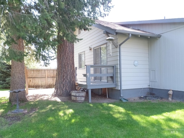 view of property exterior with a lawn and fence