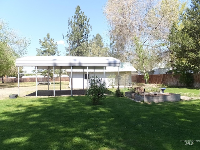 rear view of house with fence, a lawn, and a vegetable garden