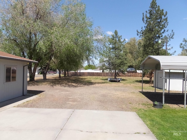 view of yard with fence and dirt driveway
