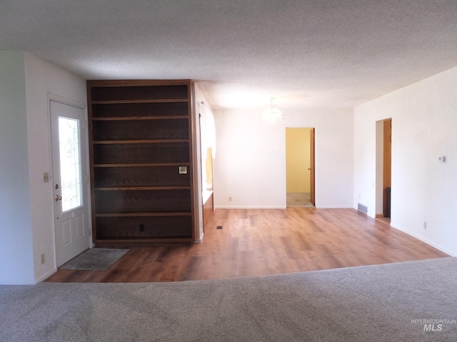 interior space with an inviting chandelier, baseboards, a textured ceiling, and wood finished floors