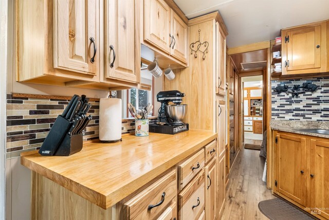 kitchen with light wood-type flooring, butcher block counters, and tasteful backsplash