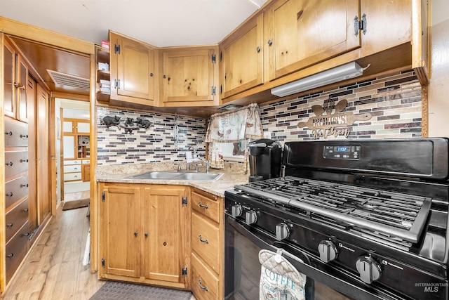 kitchen featuring sink, decorative backsplash, light hardwood / wood-style flooring, and black gas range