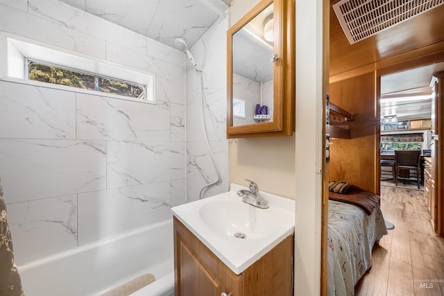 bathroom with vanity, tiled shower / bath combo, and wood-type flooring