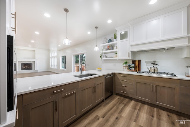 kitchen featuring a peninsula, stainless steel appliances, light countertops, a fireplace, and a sink