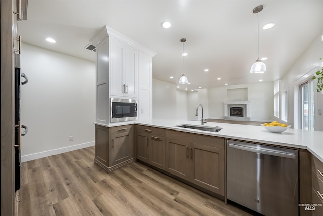 kitchen featuring stainless steel appliances, light countertops, light wood-style floors, a sink, and recessed lighting