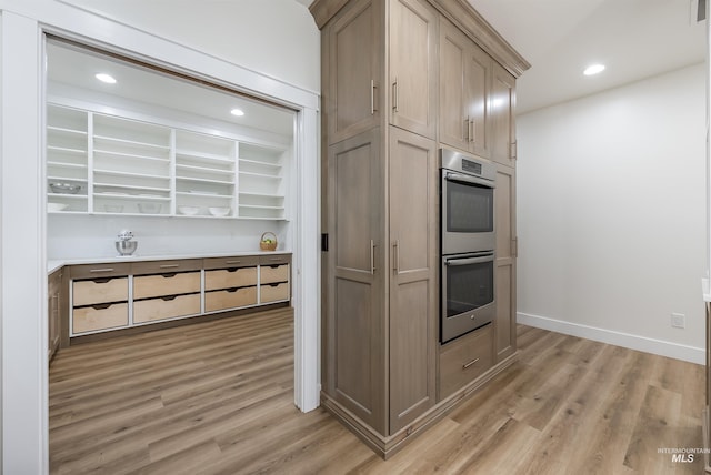 kitchen with light wood-style flooring, baseboards, stainless steel double oven, and recessed lighting