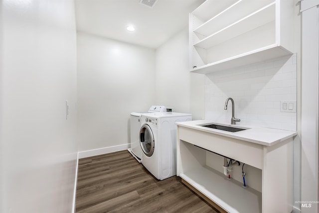 clothes washing area featuring laundry area, dark wood-style flooring, a sink, baseboards, and washing machine and clothes dryer