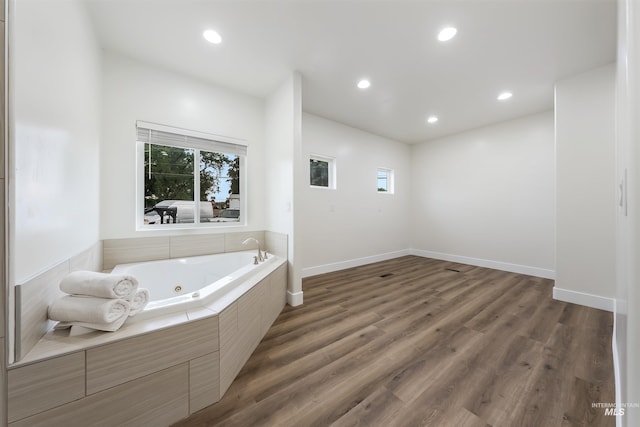 bathroom with recessed lighting, baseboards, a whirlpool tub, and wood finished floors