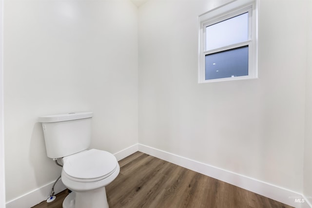 bathroom with toilet, baseboards, and wood finished floors