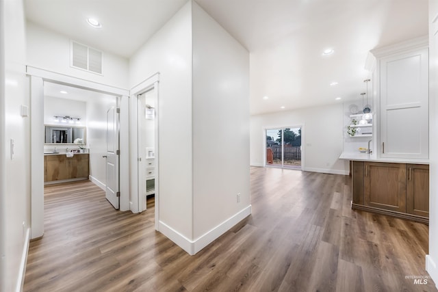 hall with baseboards, wood finished floors, visible vents, and recessed lighting