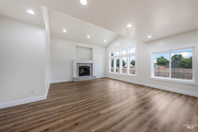 unfurnished living room with recessed lighting, a tiled fireplace, vaulted ceiling, wood finished floors, and baseboards