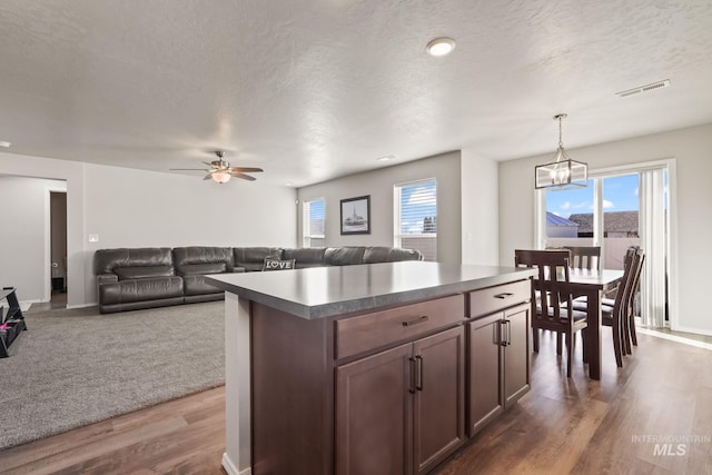 kitchen featuring hanging light fixtures, a center island, a wealth of natural light, and dark hardwood / wood-style flooring