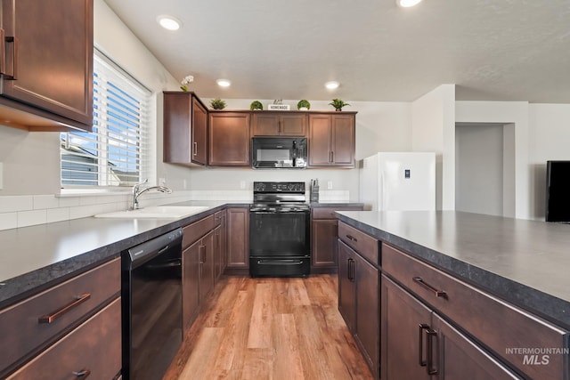 kitchen featuring dark brown cabinetry, sink, black appliances, and light wood-type flooring