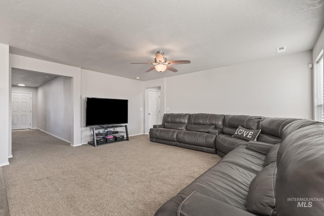 living room featuring ceiling fan, a textured ceiling, and carpet