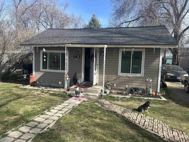 bungalow-style home with a front lawn and roof with shingles