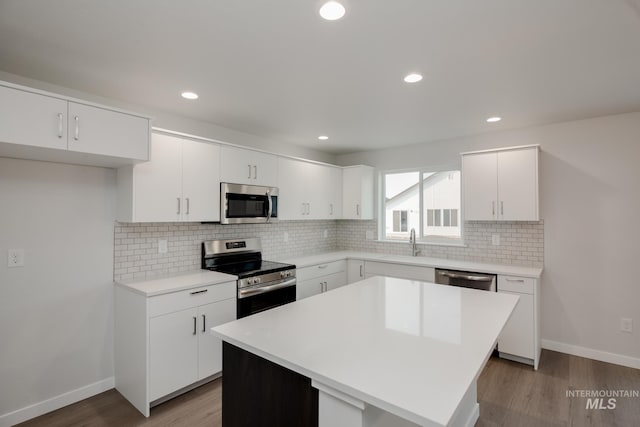 kitchen with a kitchen island, sink, white cabinets, light hardwood / wood-style floors, and stainless steel appliances