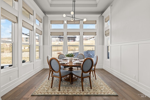 sunroom with a wealth of natural light, a tray ceiling, and a chandelier